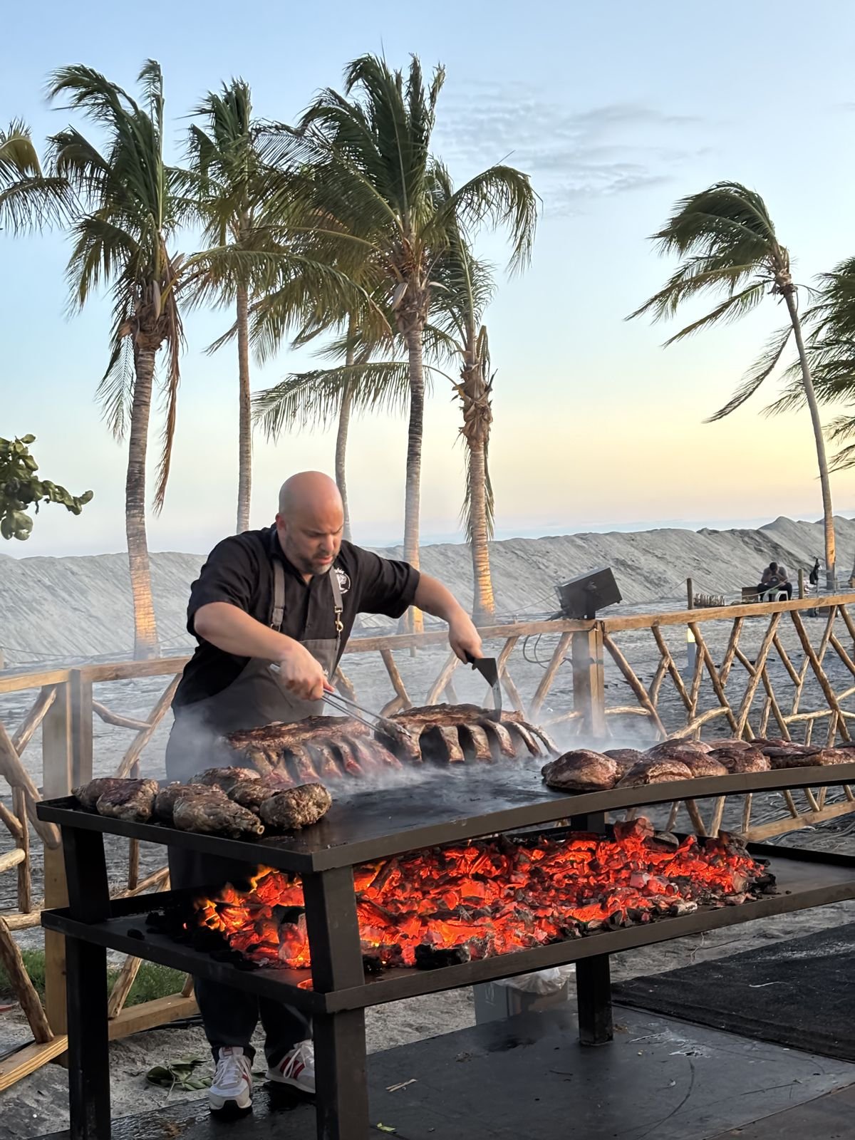 Rubén trabajando la parrilla al atardecer frente al mar